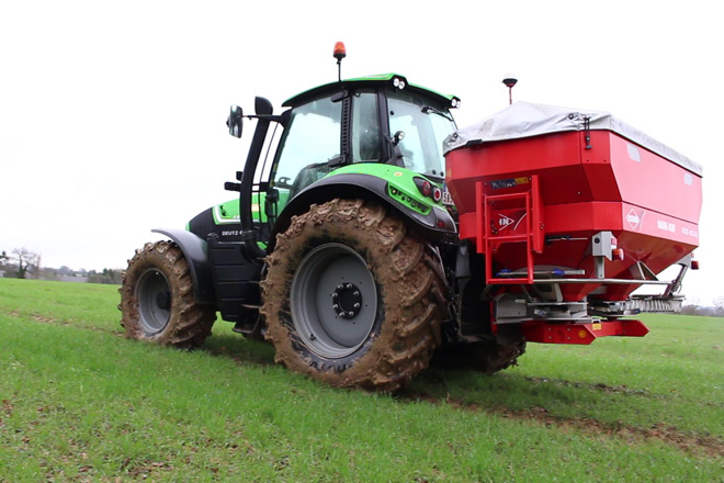 Tractor abonando un campo, dejando las marcas de las ruedas sobre la tierra